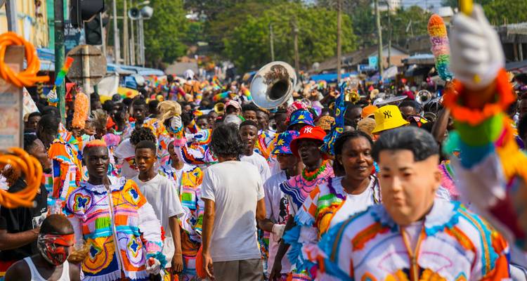 A vibrant street parade with people dressed in colorful costumes and playing musical instruments.