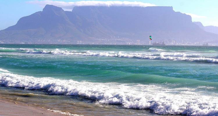 Ein Blick auf den Tafelberg mit Meereswellen, die im Vordergrund an die Küste schlagen.