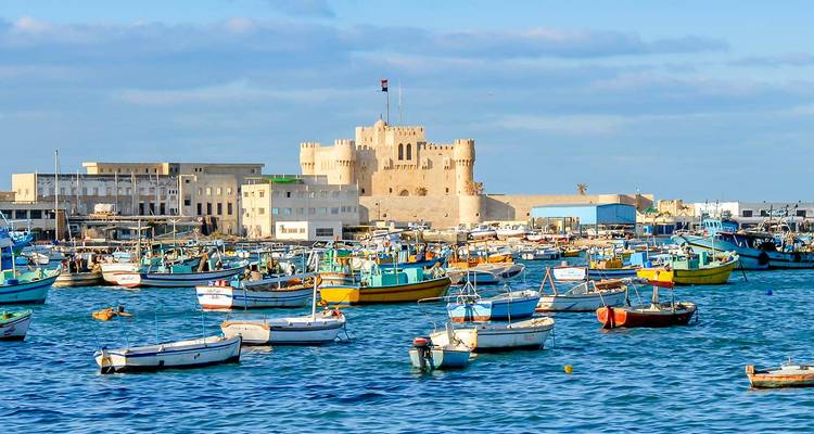 Harbor with boats and a historic fort in the background.