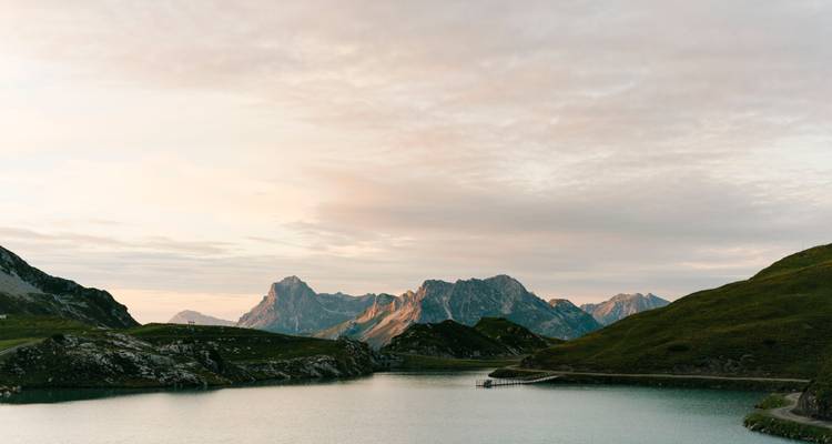 Malerische Berglandschaft mit einem See und fernen Gipfeln bei Sonnenuntergang.