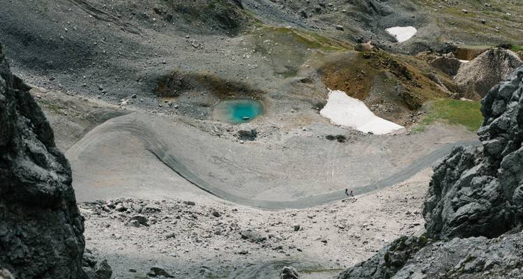 Luftaufnahme eines Tals mit einem kleinen See und felsiger Landschaft.