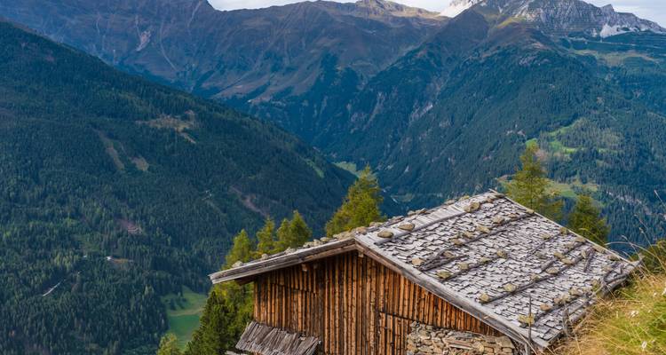 Vue de montagne avec une hutte en bois au premier plan.