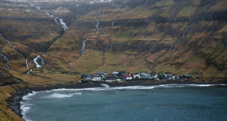 Hillside village with rugged terrain and the sea.
