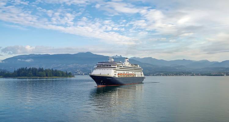 Un navire de croisière naviguant dans des eaux calmes avec des montagnes en arrière-plan.