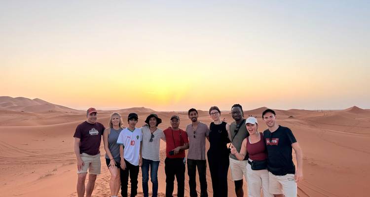 Un groupe de personnes debout dans le désert pendant le coucher du soleil.