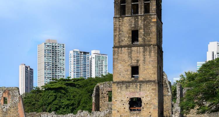 Ruines d'un bâtiment ancien avec l'horizon d'une ville moderne en arrière-plan.