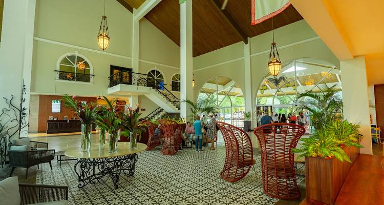 Hall d'hôtel avec des personnes, des plantes et un éclairage décoratif.