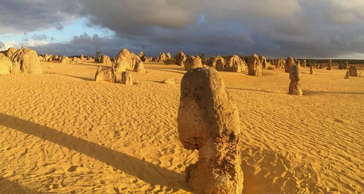 Sand landscape with unusual rock formations under a dramatic sky.