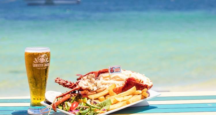 A lobster meal served with beer by the ocean.