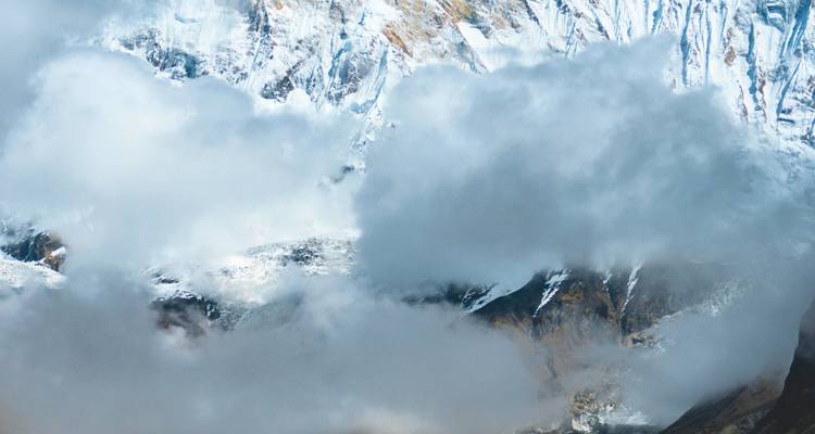 Snow-capped mountains partially covered by clouds.