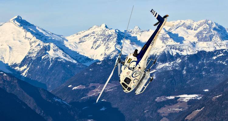 Helicopter flying with snowy mountains in the background.
