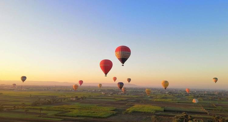 Montgolfières flottant au-dessus des champs au lever du soleil.