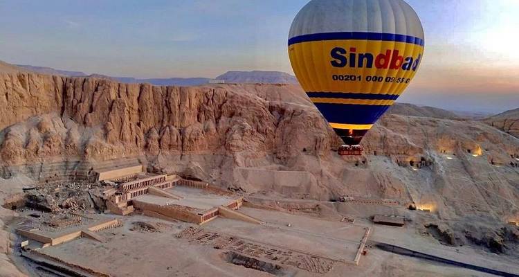 Montgolfière au-dessus de ruines antiques dans un paysage désertique.