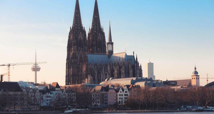 Majestic twin-spired Gothic cathedral rising above riverside skyline in warm afternoon light.