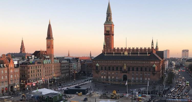 City hall square with red-brick tower bathed in the pastel hues of sunset.