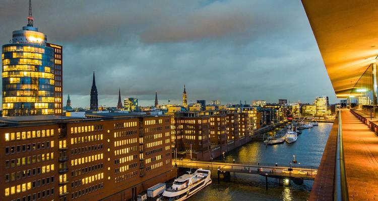 Nighttime view of modern brick warehouses and canal illuminated by city lights in Hamburg.