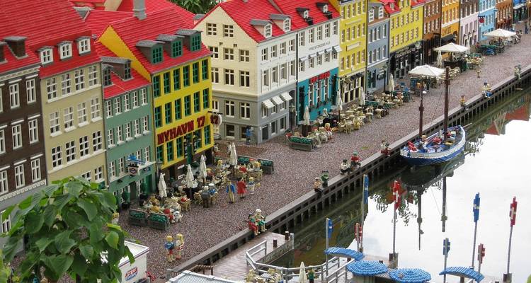 Miniature Lego model of colorful canal houses and waterfront scene reflected in water.