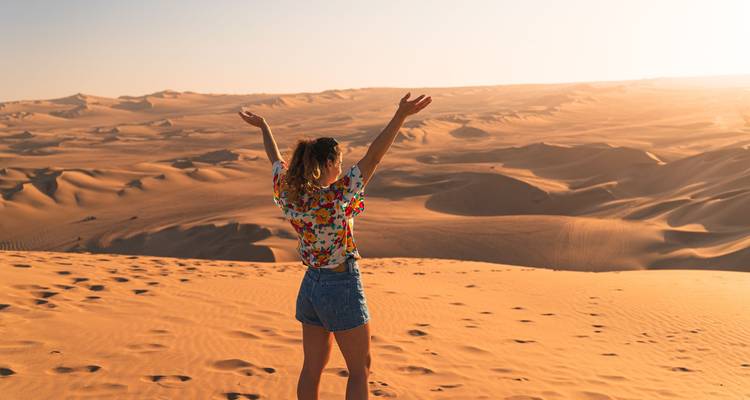 Persona de pie en un desierto con los brazos levantados.
