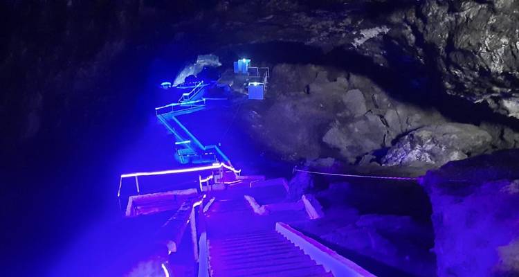 Escalera dentro de una cueva poco iluminada con luces azules.