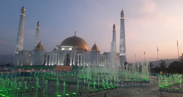 Mezquita iluminada con fuentes al atardecer.