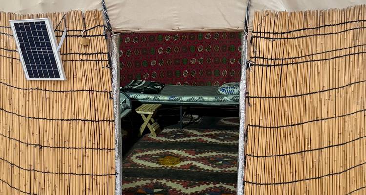 Innenraum einer traditionellen Jurte mit Betten und Teppichen.