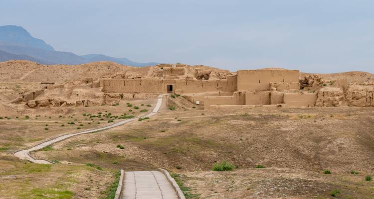 Ancient ruins located in a desert landscape with distant mountains.