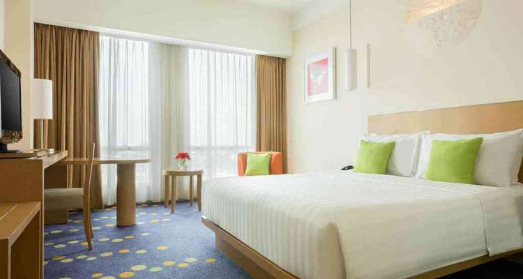 Hotel room with king-sized bed and colorful decor.