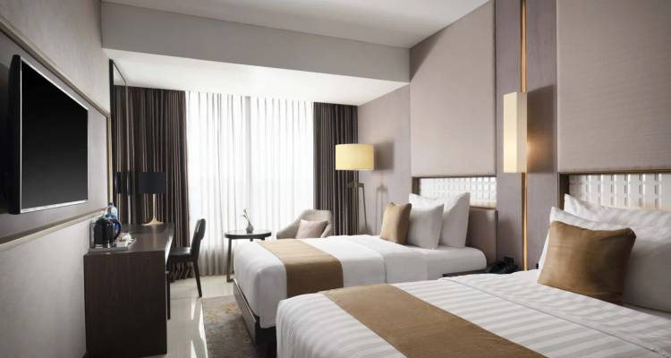 Modern hotel room with twin beds and elegant decor.