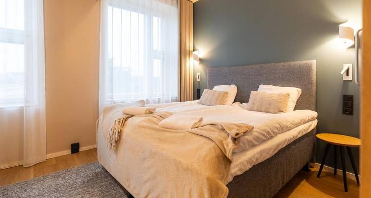 Chambre d'hôtel simple avec un lit double et un éclairage tamisé.