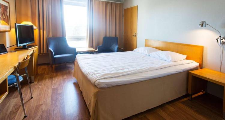 Chambre d'hôtel basique avec mobilier en bois et une grande fenêtre.