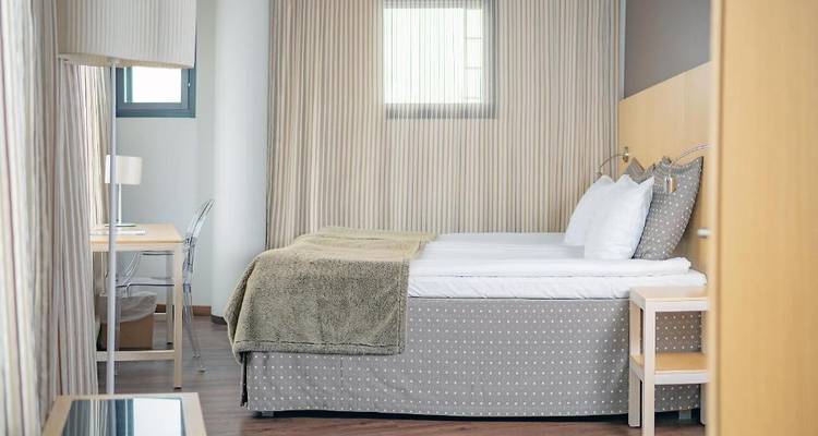 Chambre d'hôtel moderne avec literie et rideaux à motifs.