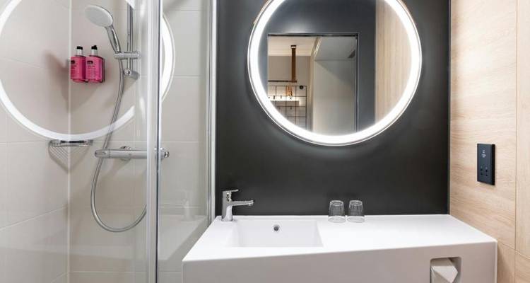 Salle de bain moderne avec un miroir circulaire éclairé et un lavabo.
