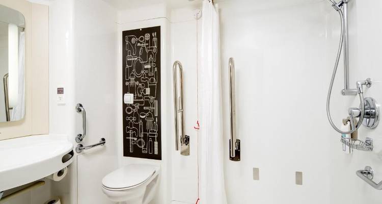 Salle de bain blanche avec équipements d'accessibilité.