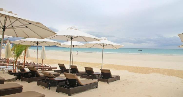 Strandresort mit Sonnenliegen und Sonnenschirmen an einem Sandstrand.