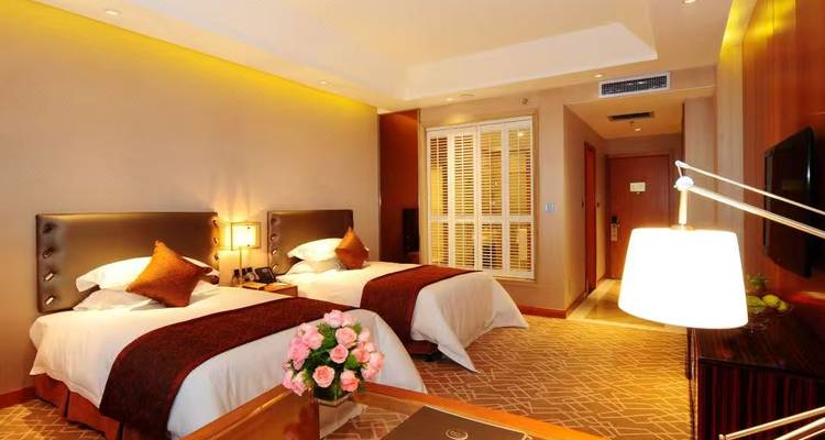 Luxueuze hotelkamer met twee bedden en warme verlichting.