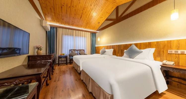 Hotelkamer met gezellige tweepersoonsbedden en houten wanden.