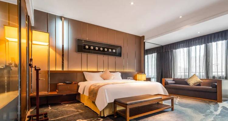 Stilvolles Hotelzimmer mit Kingsize-Bett, Sofa, großen Fenstern und zeitgenössischer Einrichtung
