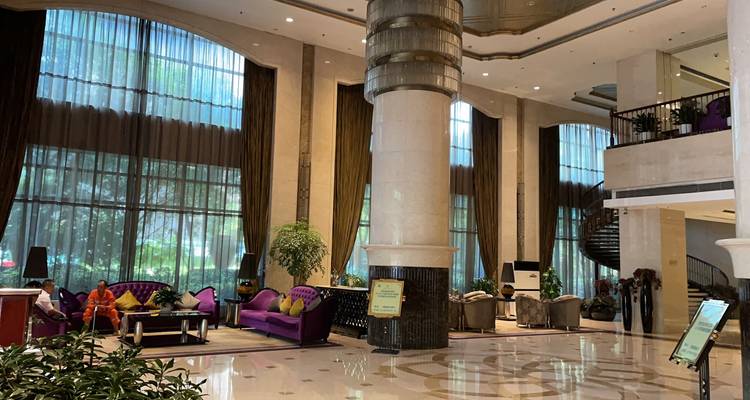 Geräumige Hotellobby mit hoher Säule, moderner Einrichtung und großen Glasfenstern