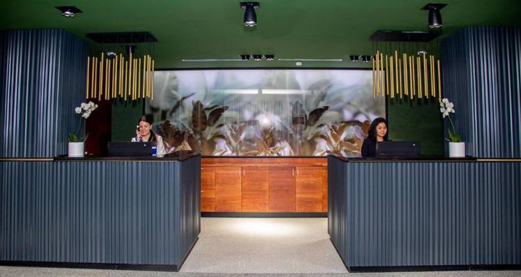 Hotel reception area with two receptionists behind a modern desk.