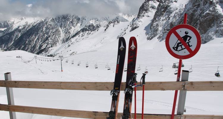 Schneebedeckte Berggipfel mit Skiern und einem Skiverbotsschild.