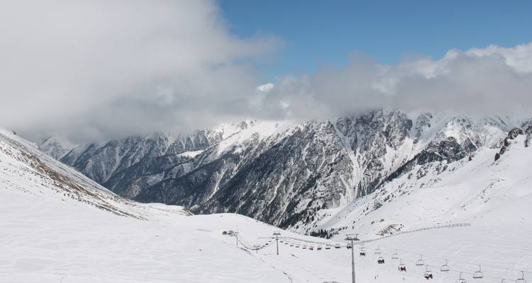 Weite Landschaftsansicht verschneiter Berge, teilweise von Wolken verdeckt.