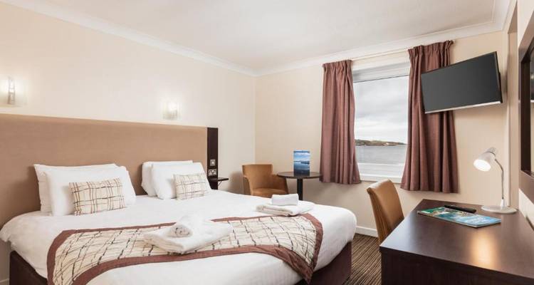 Chambre d'hôtel confortable avec vue sur la mer par la fenêtre.