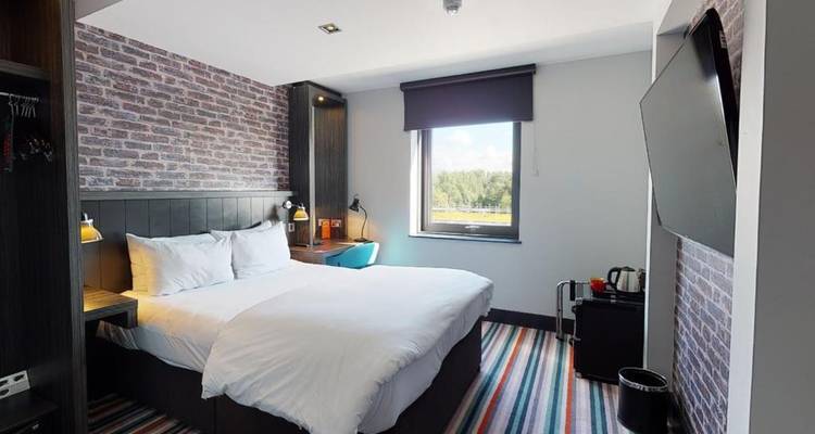 Chambre d'hôtel moderne avec un mur de briques élégant and un tapis rayé.