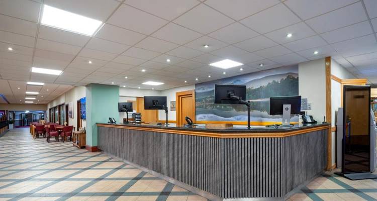 Zone de réception dans un hôtel avec des écrans d'ordinateur et un papier peint mural.