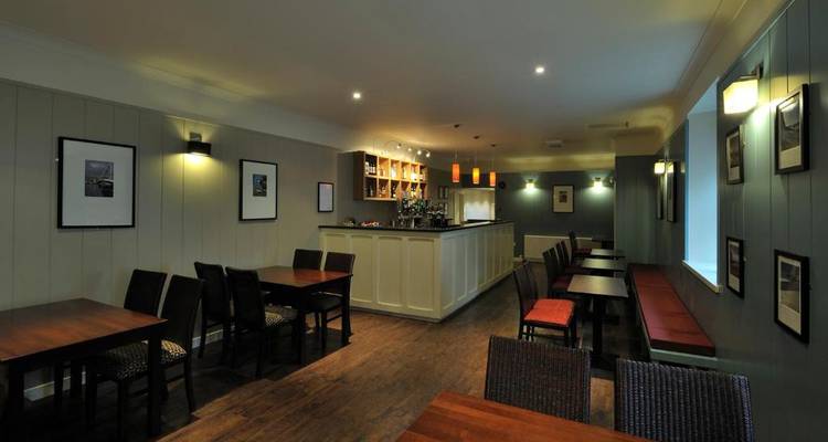 Zone de bar faiblement éclairée avec des places assises et une sélection de boissons.