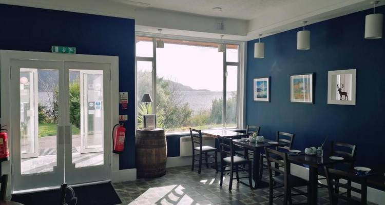 Petite salle à manger avec vue sur un lac à travers de grandes fenêtres.