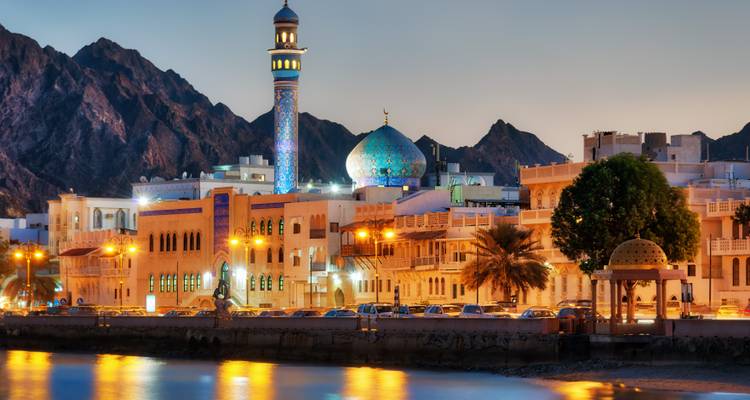 Wunderschöner Blick auf eine Moschee nahe dem Meer mit Bergen im Hintergrund in der Abenddämmerung.