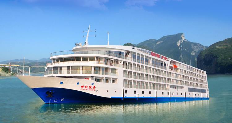 Un gran crucero fluvial de múltiples cubiertas en aguas turquesas enmarcado por montañas verdes escarpadas bajo un cielo despejado.