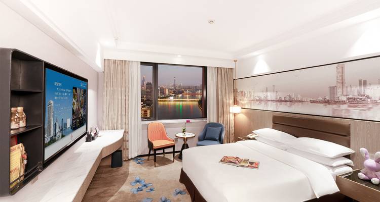 Hotelzimmer mit einem großen Bett, Stadtblick und moderner Einrichtung.