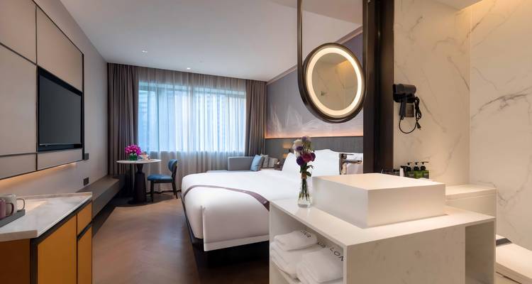 Habitación moderna de hotel con cama king size, ventana grande y baño de mármol minimalista.